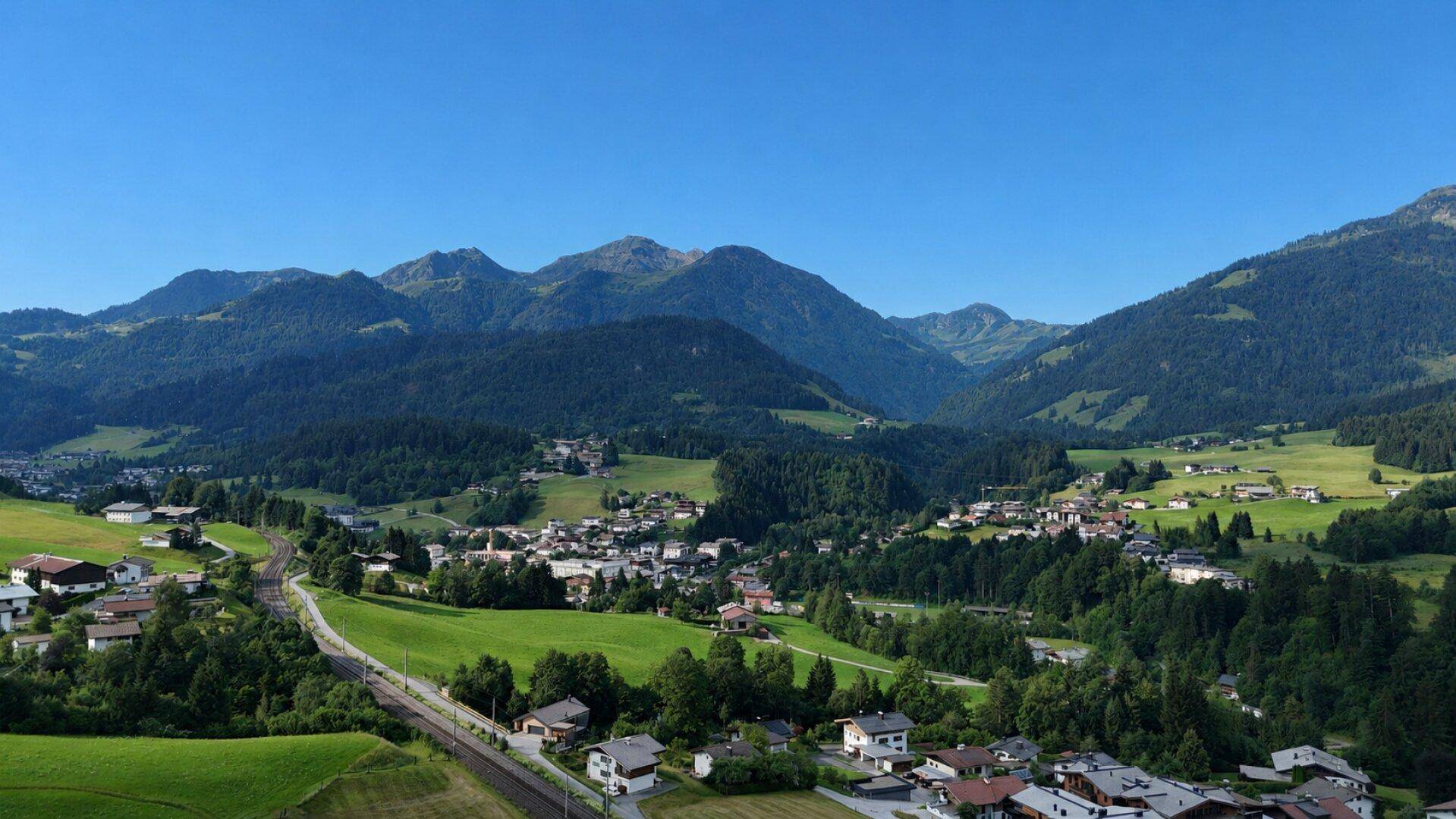 Weitläufiger Panoramablick auf ein malerisches Dorf, eingebettet in eine grüne Berglandschaft.