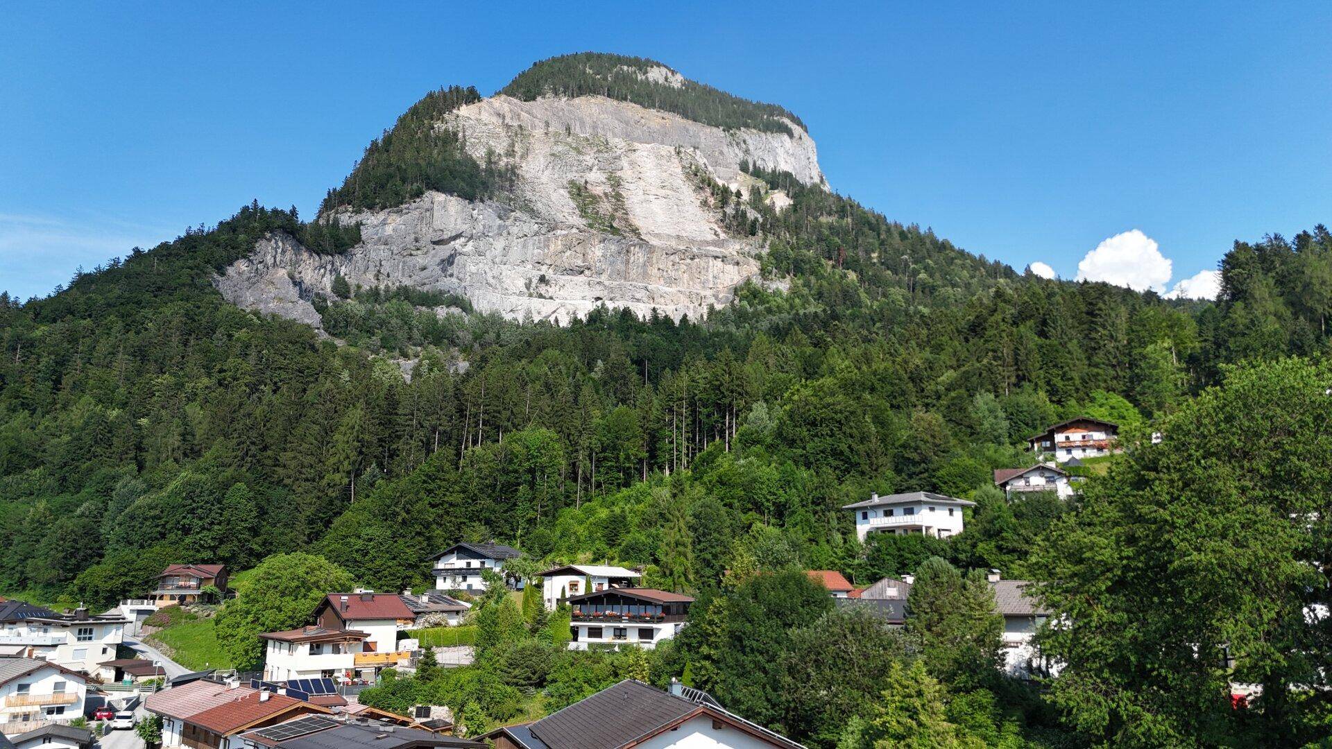 Malerischer Blick auf einen majestätischen Berg mit Häusern in den grünen Ausläufern.