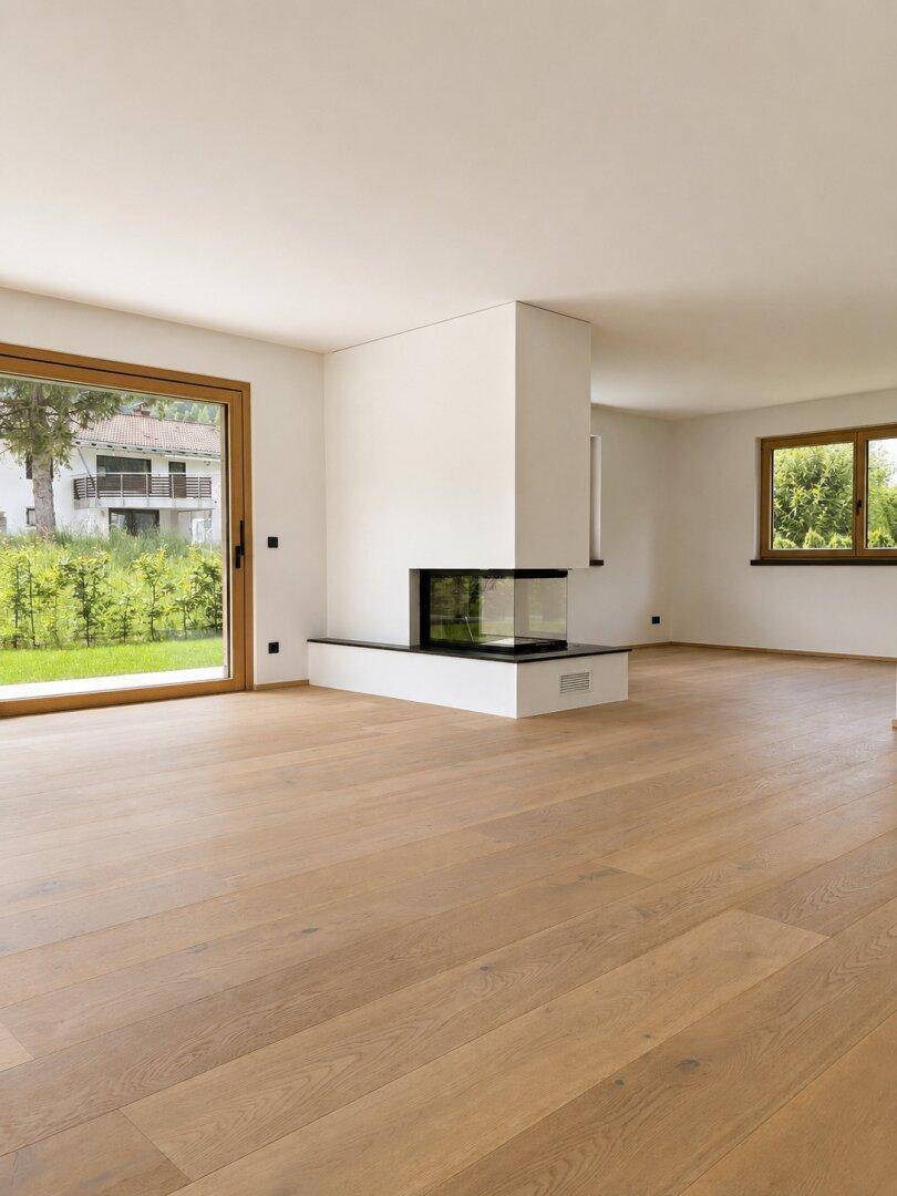 Geräumiges Wohnzimmer mit Eichenparkett, Zugang zum Garten und einem modernen, freistehenden Kamin.