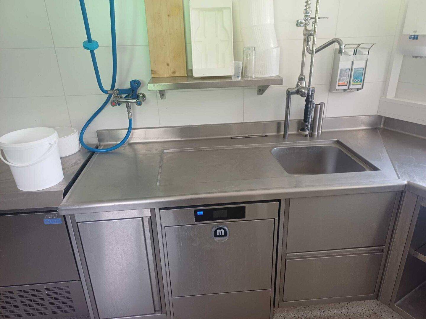 Edelstahl-Arbeitsplatte mit integriertem Spülbecken und Geschirrspüler in einem funktionalen Bereich.
