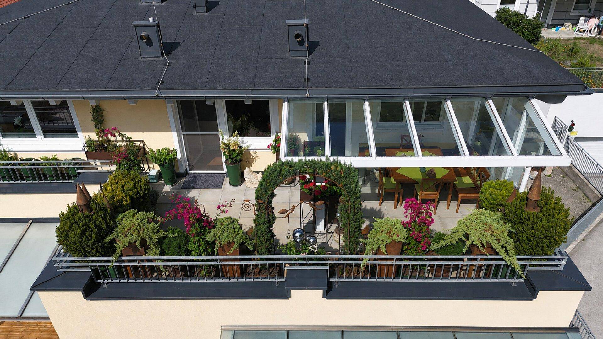 Dachterrasse mit Wintergarten und üppiger Bepflanzung, bietet einen erweiterten Wohnraum im Freien.