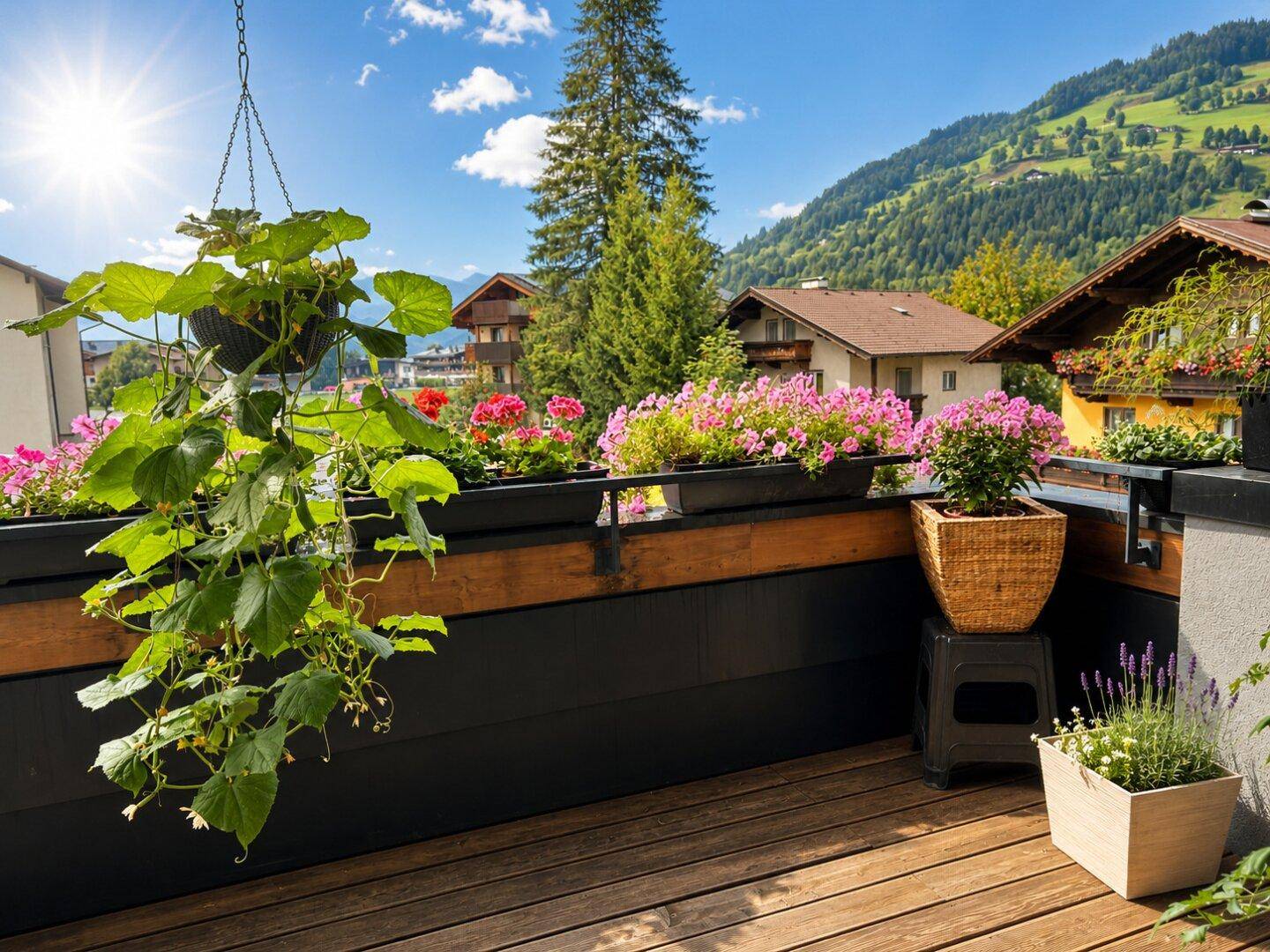 Sonniger Balkon mit Holzdeck, bunten Blumenkästen und malerischem Blick auf die Berglandschaft.