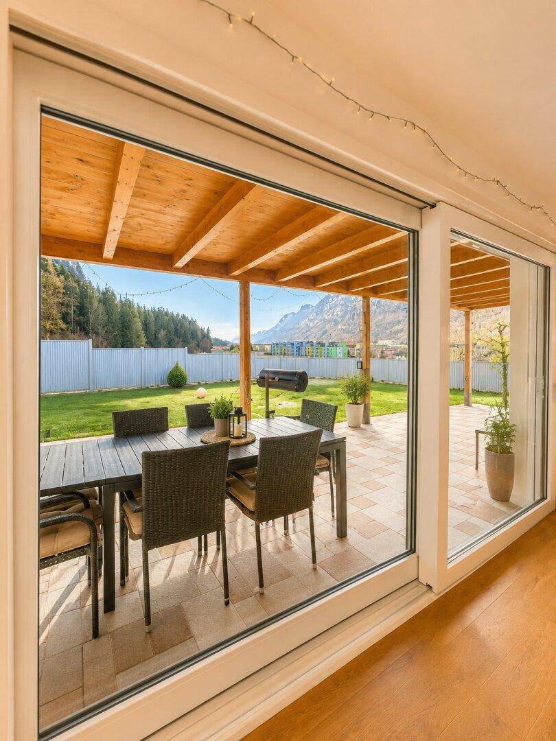 Große Terrasse mit Esstisch und Bergblick, umgeben von einem gepflegten Garten.