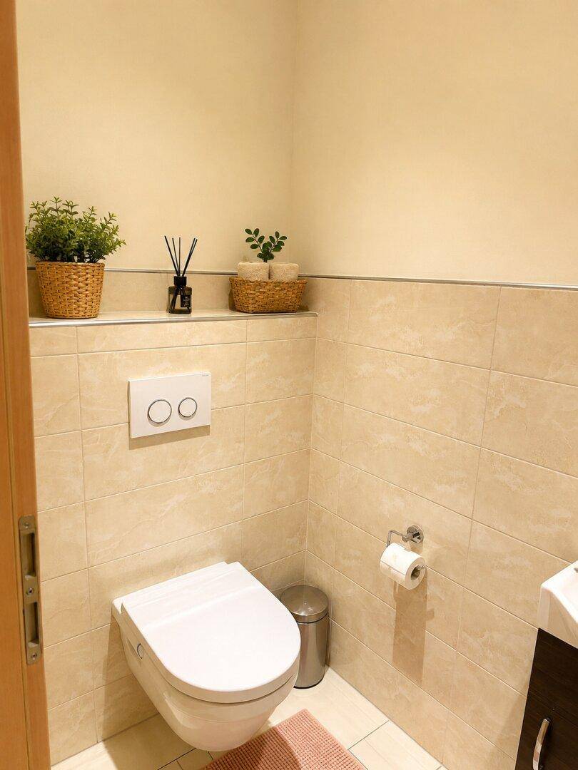 Modernes Gäste-WC mit wandhängendem WC, kleinem Waschbecken und hellen Fliesen.