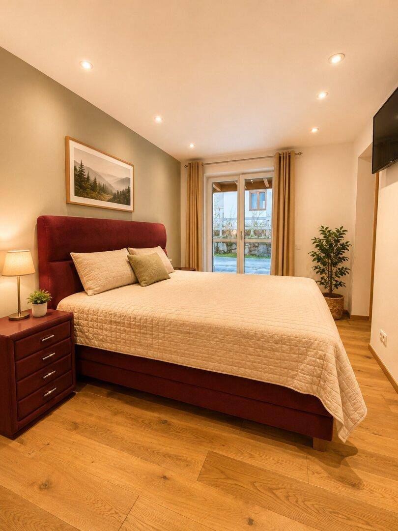 Komfortables Schlafzimmer mit Doppelbett, Holzboden und Zugang zum Außenbereich.