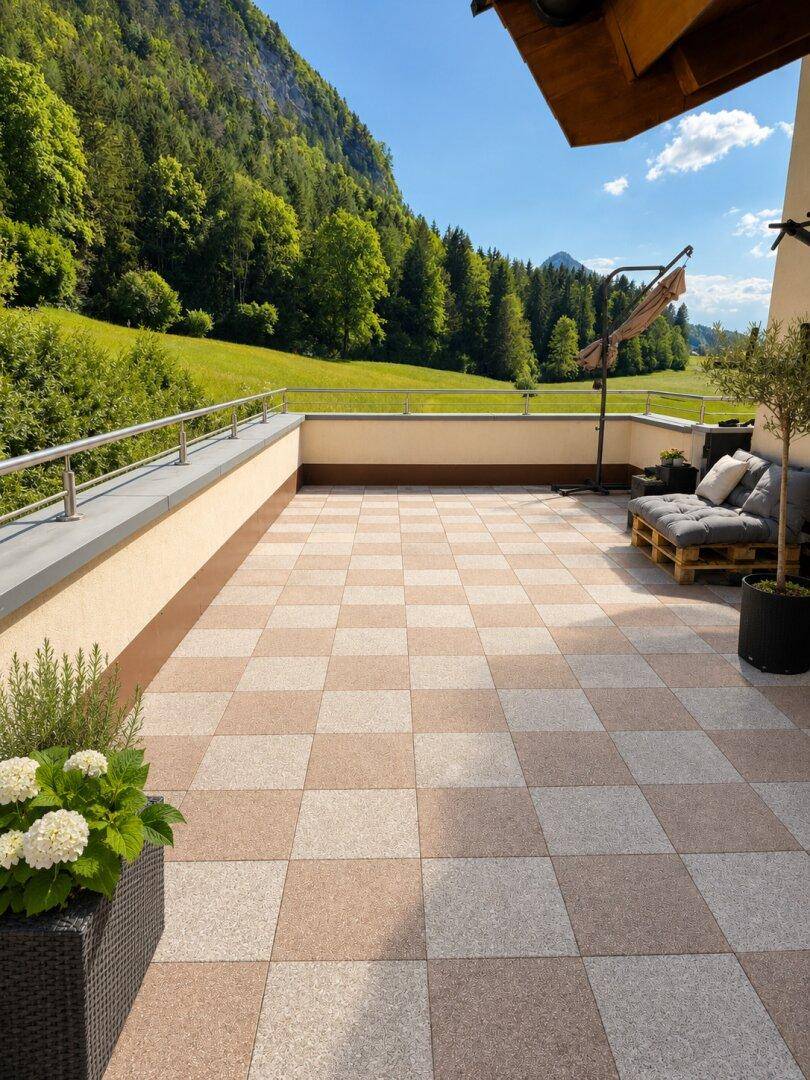 Sonnige Terrasse mit kariertem Fliesenboden, gemütlicher Sitzecke und beeindruckendem Blick auf die umliegende Natur.