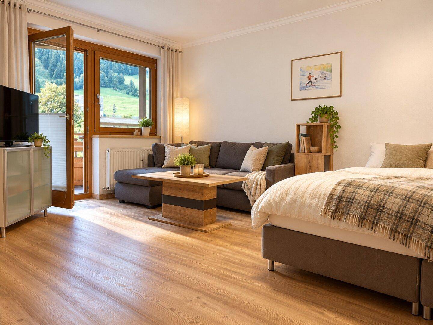 Gemütlicher Wohnbereich mit Sofa, Bett und Zugang zu einem Balkon mit Bergblick.