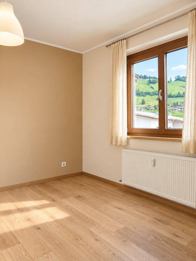 Unmöbliertes Schlafzimmer mit Laminatboden, hellen Wänden und Fenster mit grüner Aussicht.
