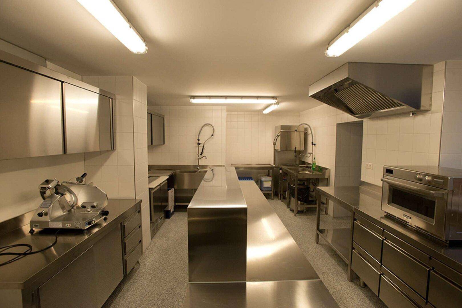 Professionelle Industrieküche mit Edelstahlmöbeln, Arbeitsflächen und Geräten, ideal für Gastronomiebetriebe.