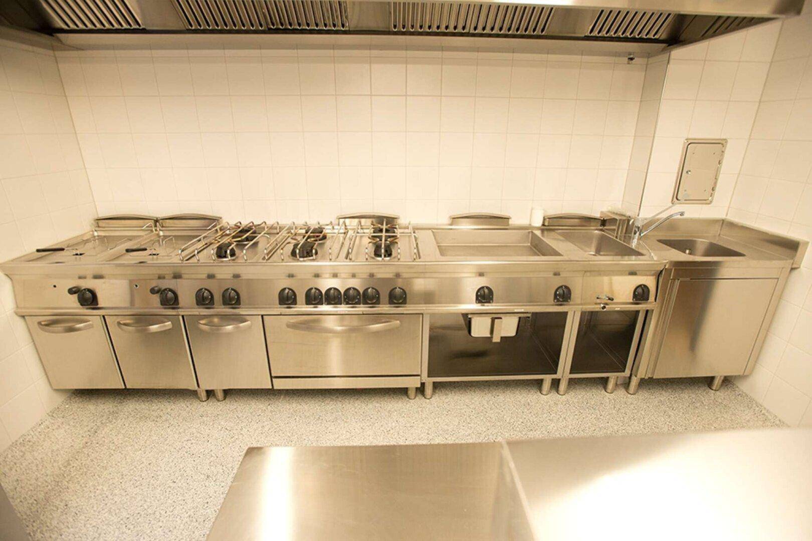 Nahaufnahme einer professionellen Gaskochstelle mit mehreren Brennern und integrierten Fritteusen in der Küche.