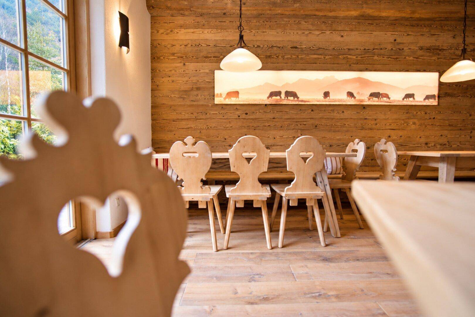 Detailansicht von traditionellen Holzstühlen mit Herzmotiven und rustikaler Holzvertäfelung im Speisesaal.