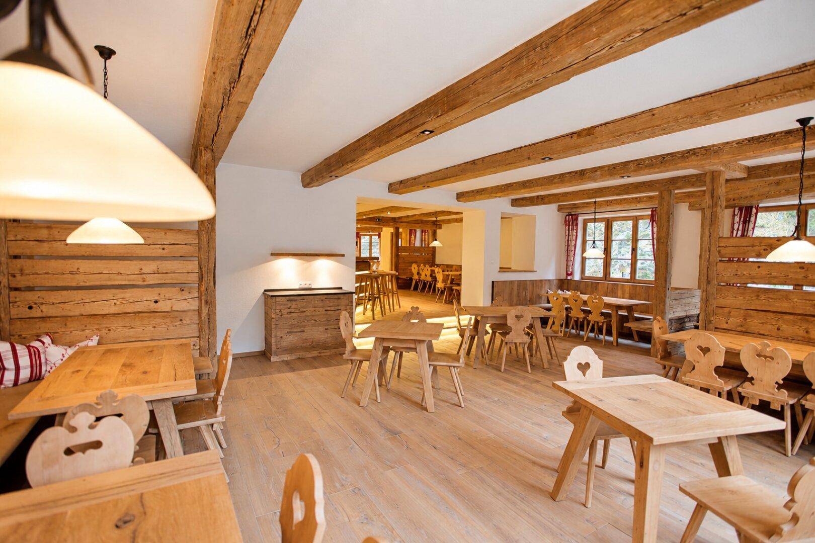 Großer, offener Speisebereich mit zahlreichen Holztischen, Bänken und sichtbaren Deckenbalken.