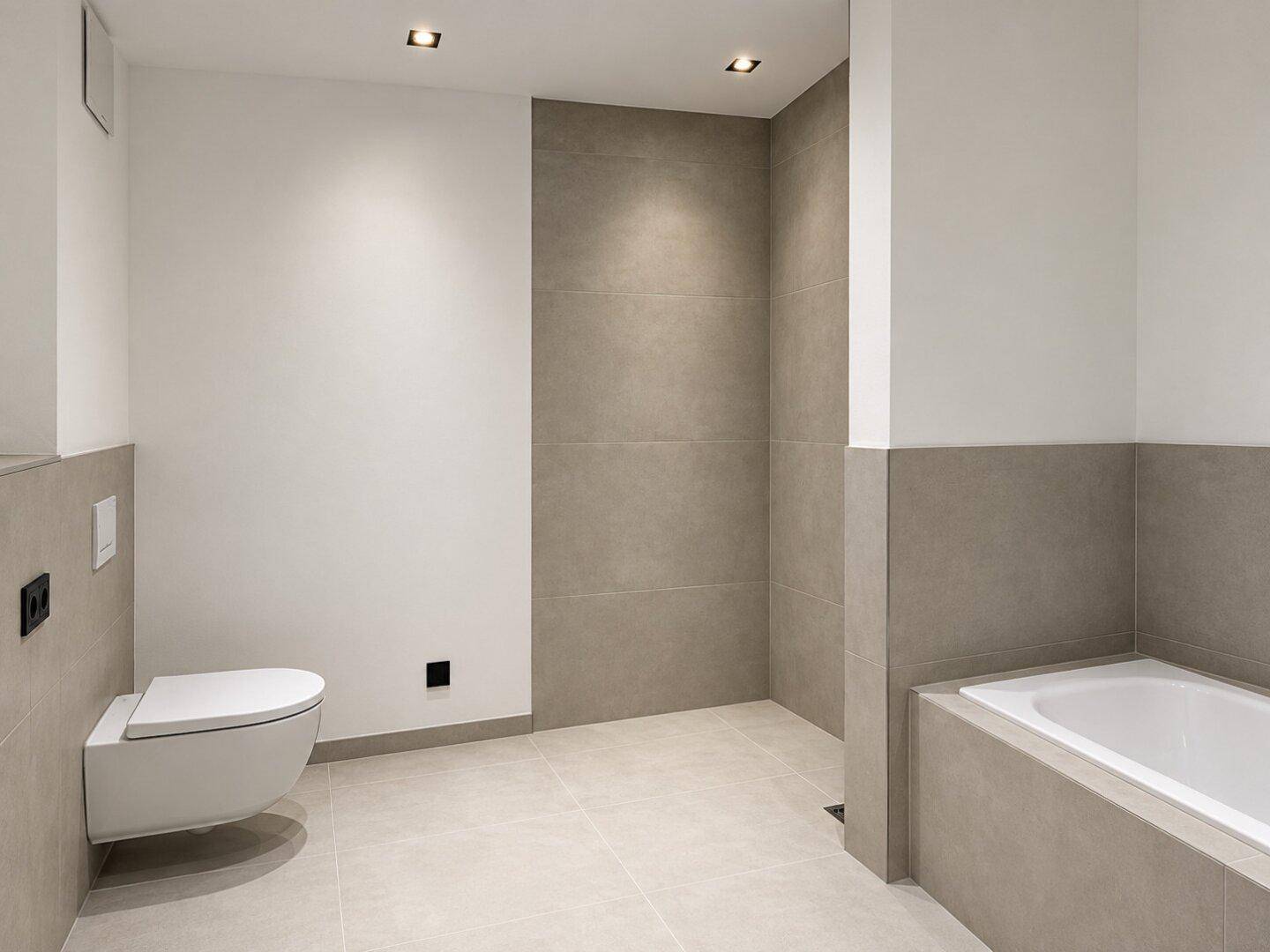 Modernes Badezimmer mit grauen Fliesen, wandhängendem WC und integrierter Badewanne.