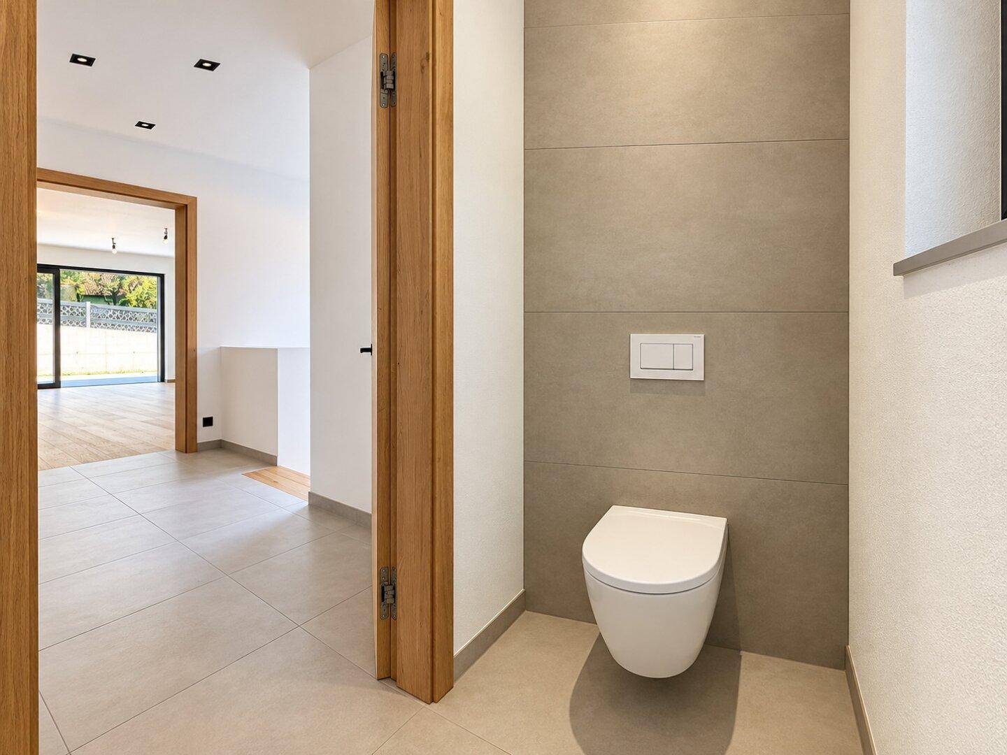 Kleines, modernes Gäste-WC mit wandhängender Toilette und grauen Wandfliesen.