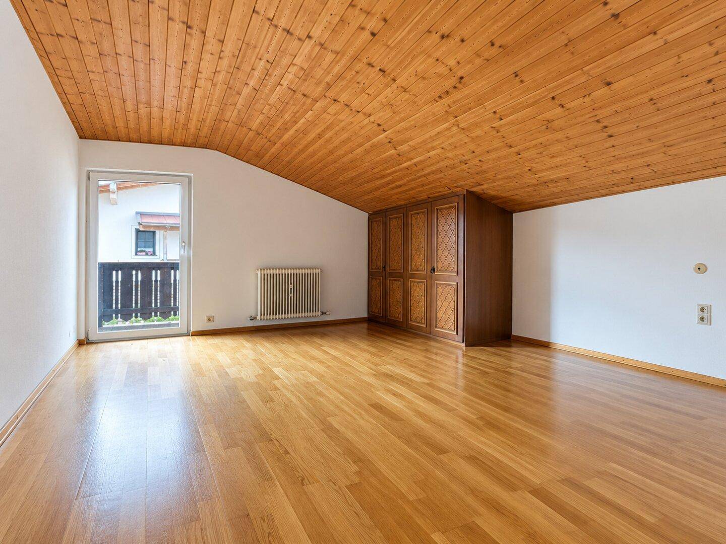 Gemütliches Schlafzimmer mit Holzboden, Holzdecke und Balkonzugang.