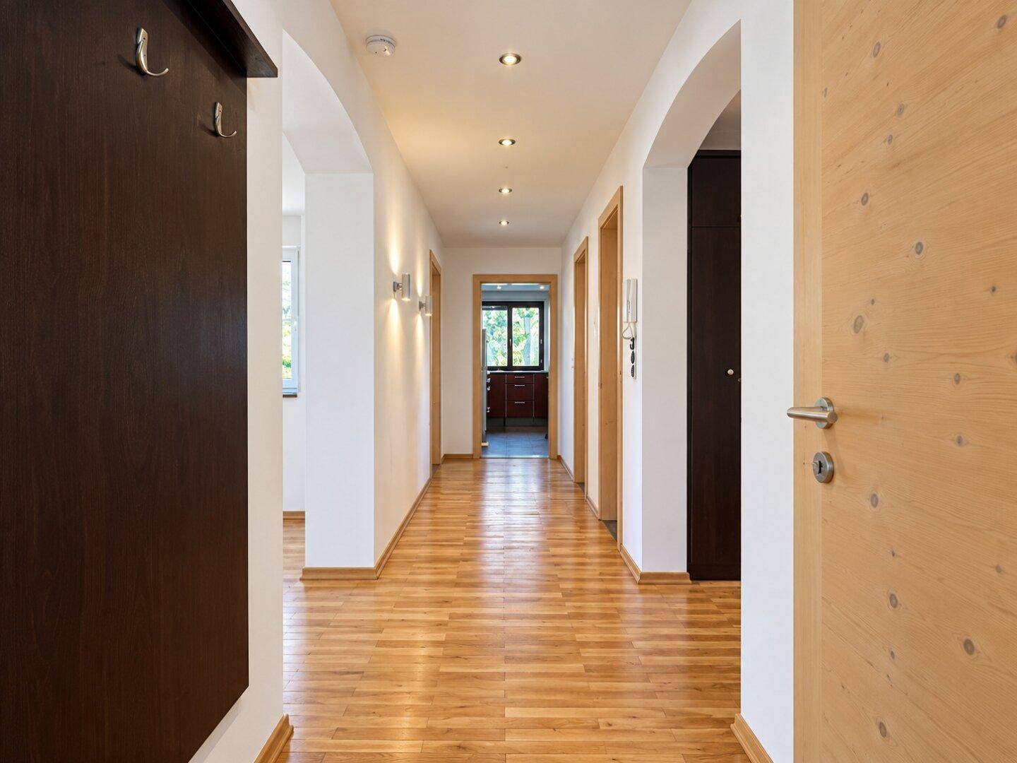 Langer, heller Flur mit Holzboden, Einbauschrank und Zugang zu weiteren Zimmern.