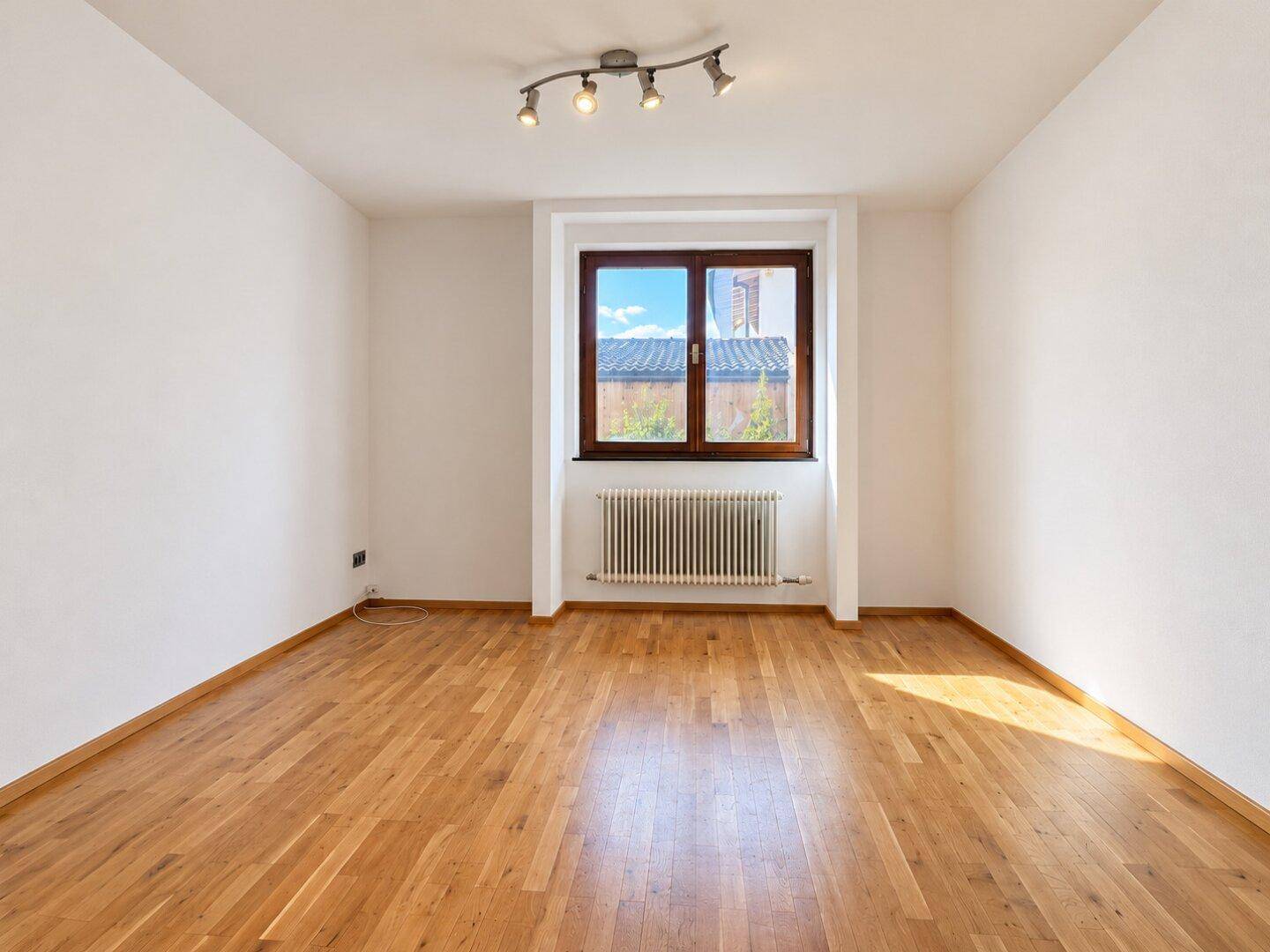 Gemütliches Schlafzimmer mit Holzboden und einem Fenster, das viel Licht spendet.