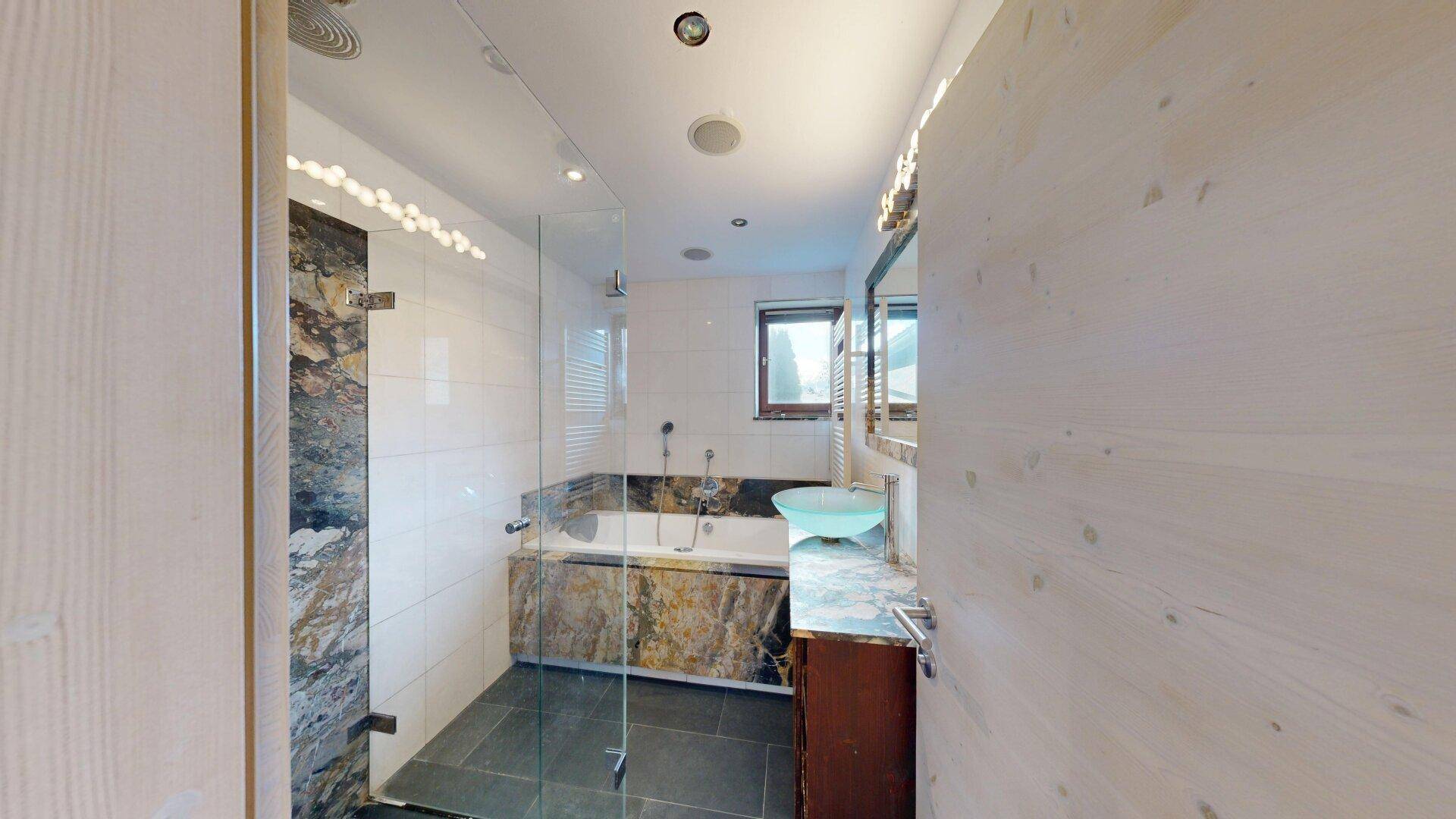 Modernes Badezimmer mit Badewanne, Duschkabine und stilvollem Waschbecken, teilweise gefliest.
