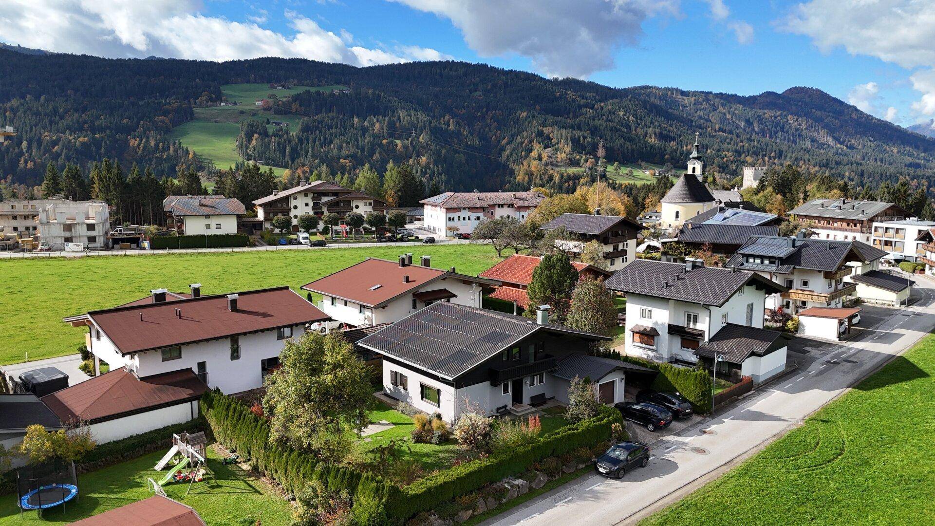 Malerische Wohngegend mit Häusern, grünen Wiesen und beeindruckendem Bergblick.