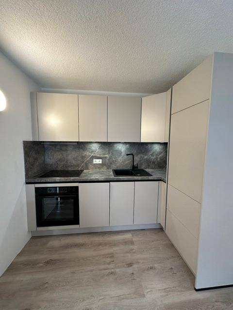 Helle, moderne Küche mit integrierten Geräten, Laminatboden und viel natürlichem Licht.