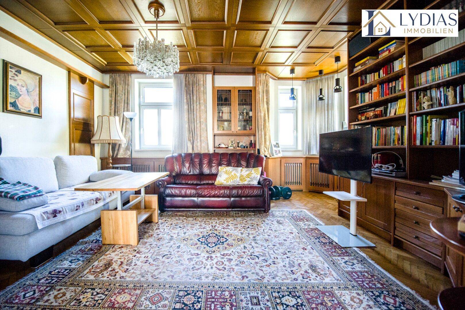 Gemütliches Wohnzimmer mit Holzkassettendecke, Parkettboden und traditionellen Möbeln.