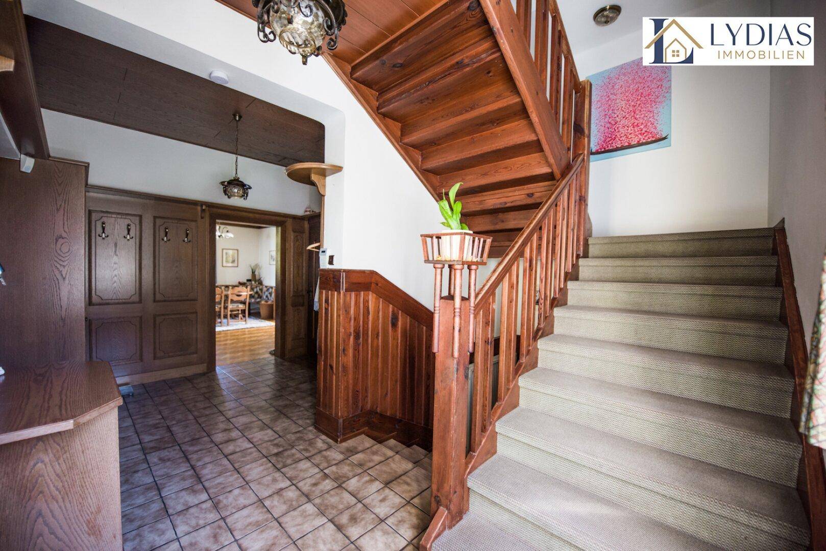 Eingangsbereich mit Holztreppe, Fliesenboden und traditionellen Holzelementen.