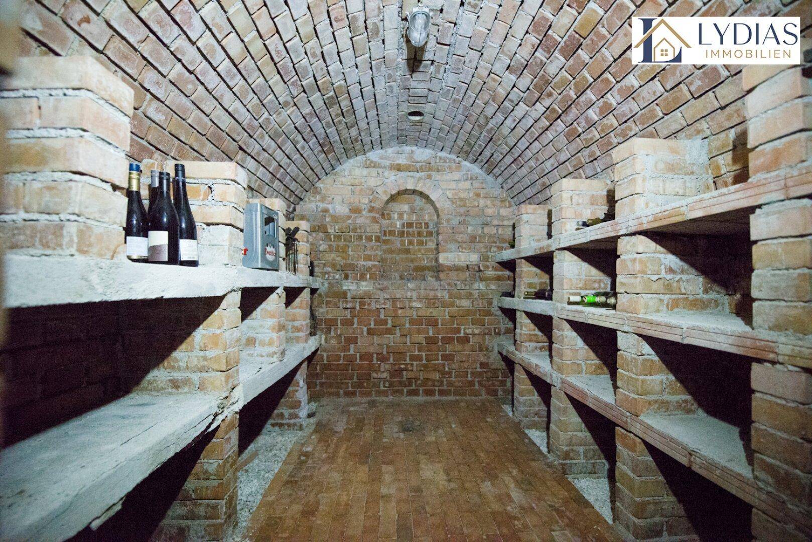 Historischer Weinkeller mit Ziegelgewölbe und Holzregalen, ideal zur Weinlagerung.