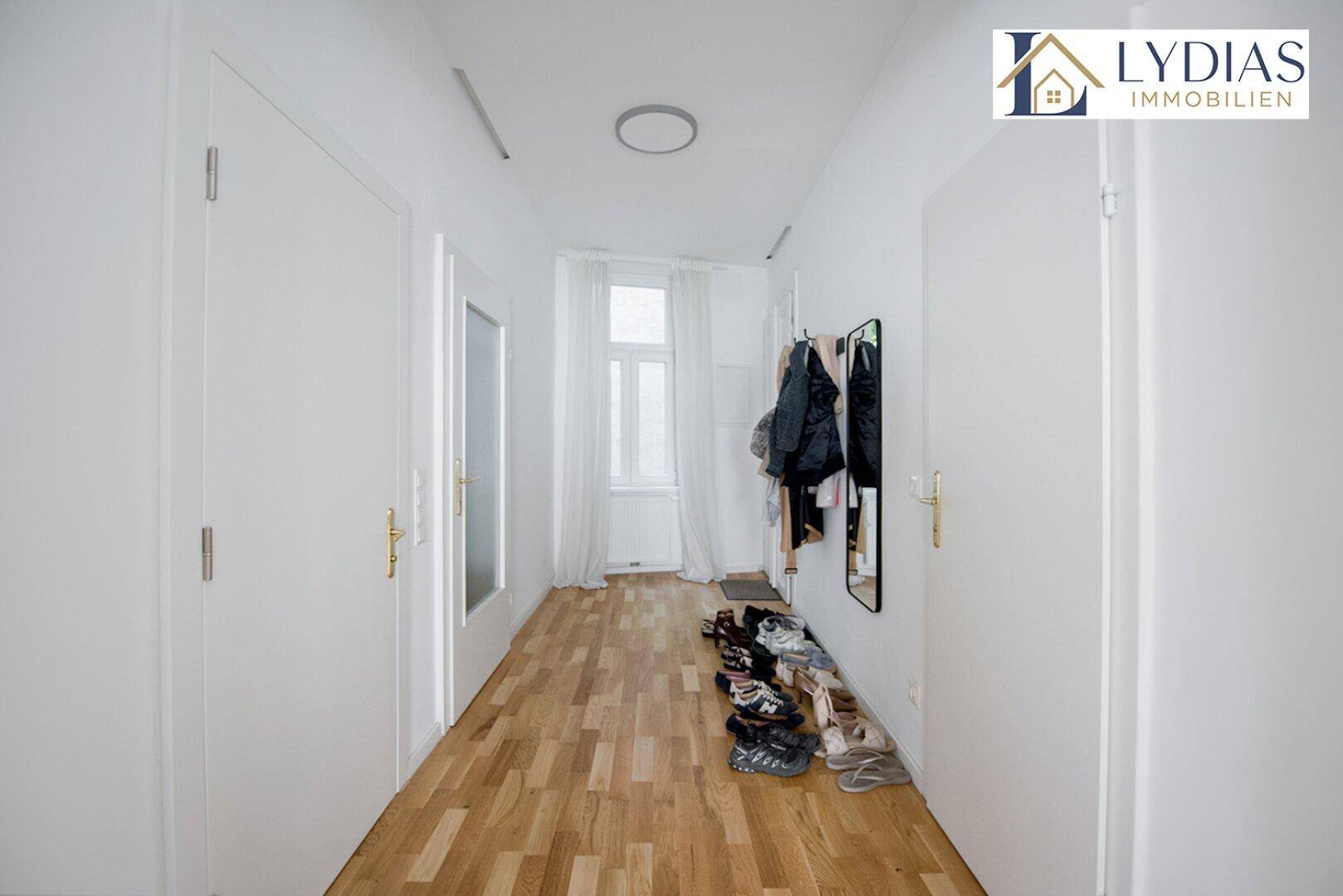 Heller Flur mit Holzboden, weißen Türen und Garderobe.