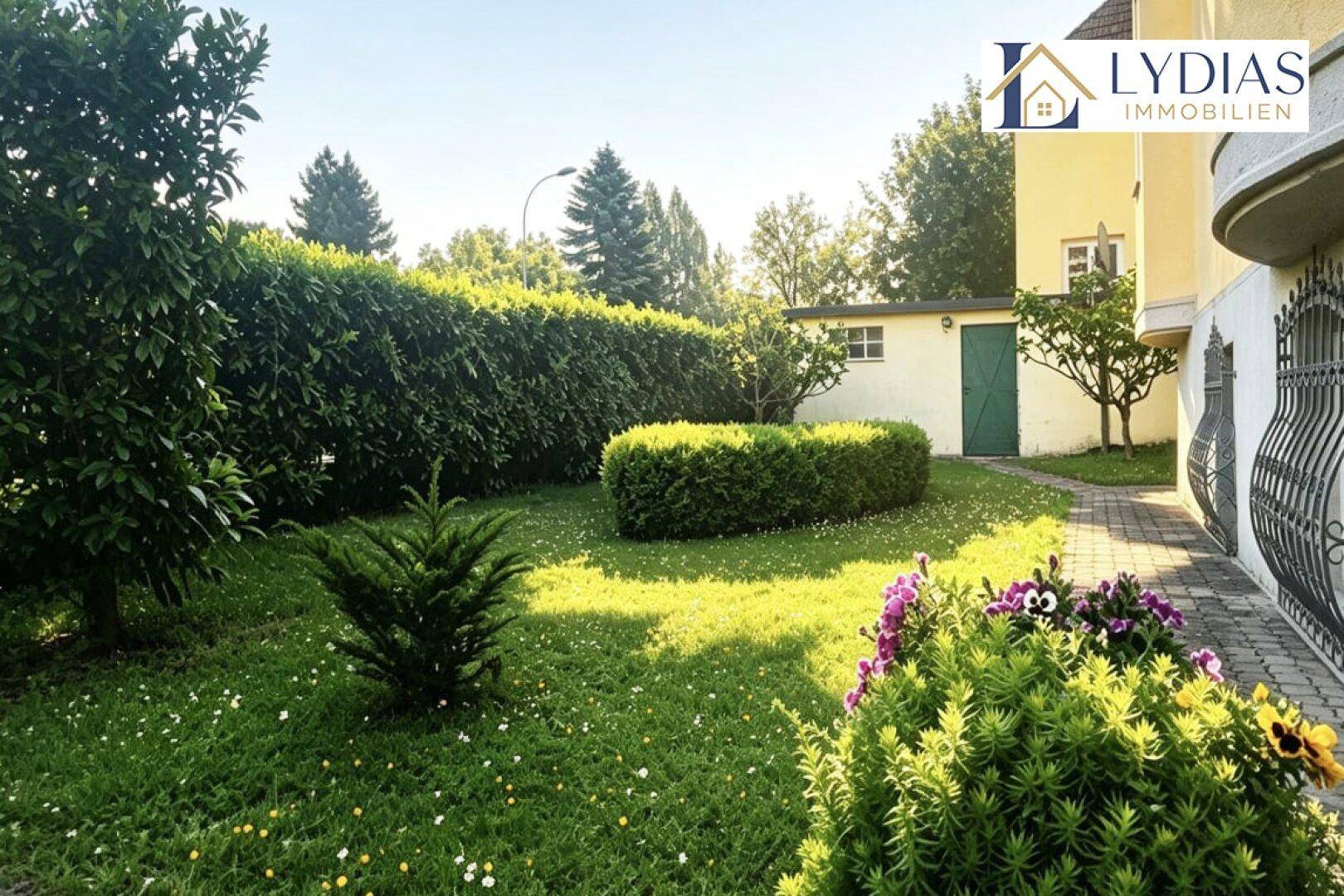 Gepflegter Vorgarten mit Rasenfläche, hohen Hecken und einem kleinen Gartenhaus neben dem Gebäude.