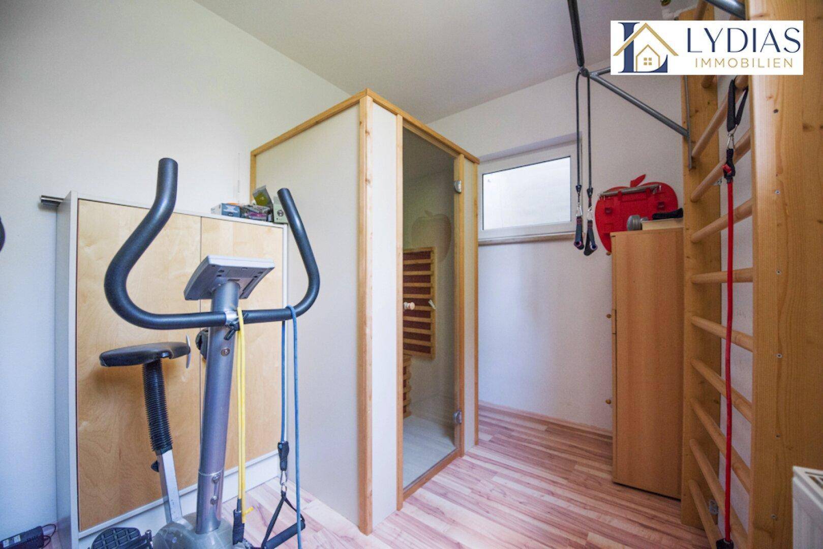 Fitnessraum im Untergeschoss mit Trainingsgeräten und einer integrierten Sauna.