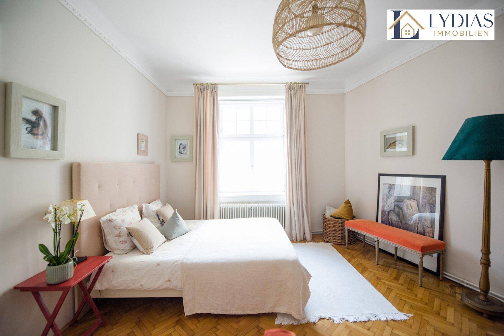 Gemütliches Schlafzimmer mit hellem Parkettboden und einem großen Fenster für viel Tageslicht.