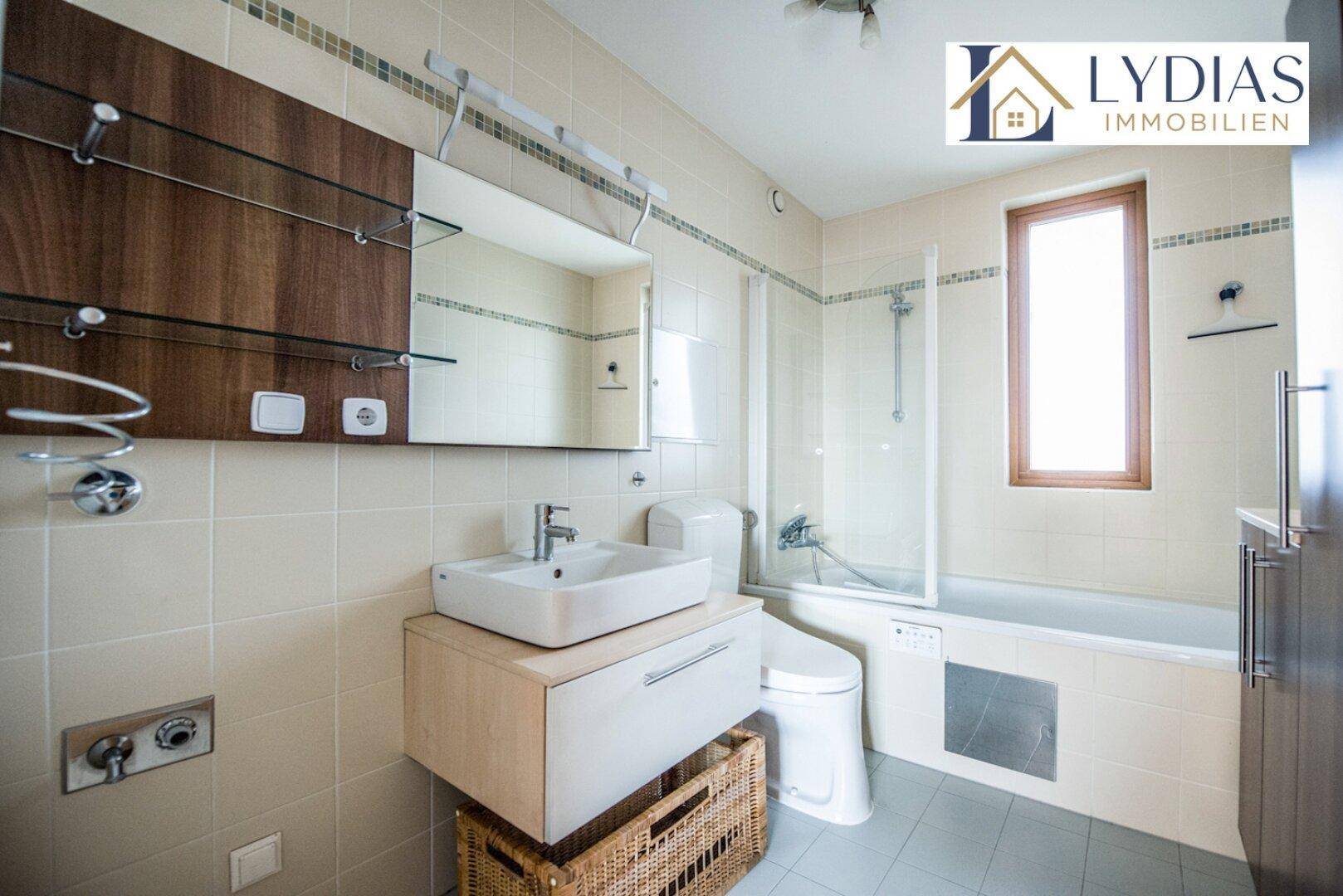 Modernes Badezimmer mit Badewanne, Dusche und Fenster, hell gefliest.