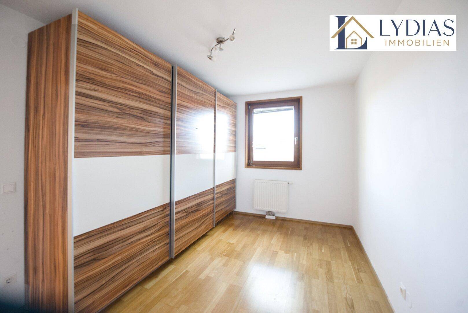 Schlafzimmer mit großem Einbauschrank und Holzboden, hell und funktional eingerichtet.