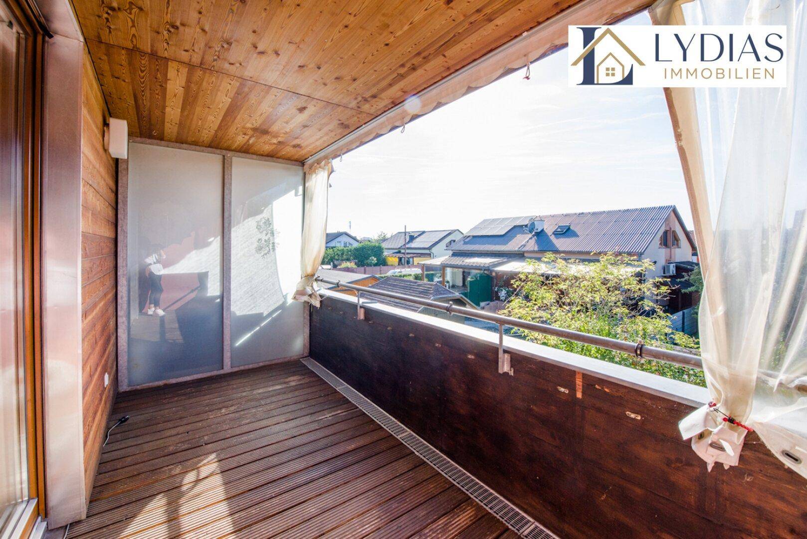 Gemütlicher Balkon mit Holzboden und seitlicher Verglasung, geschützt vor Wind und Wetter.
