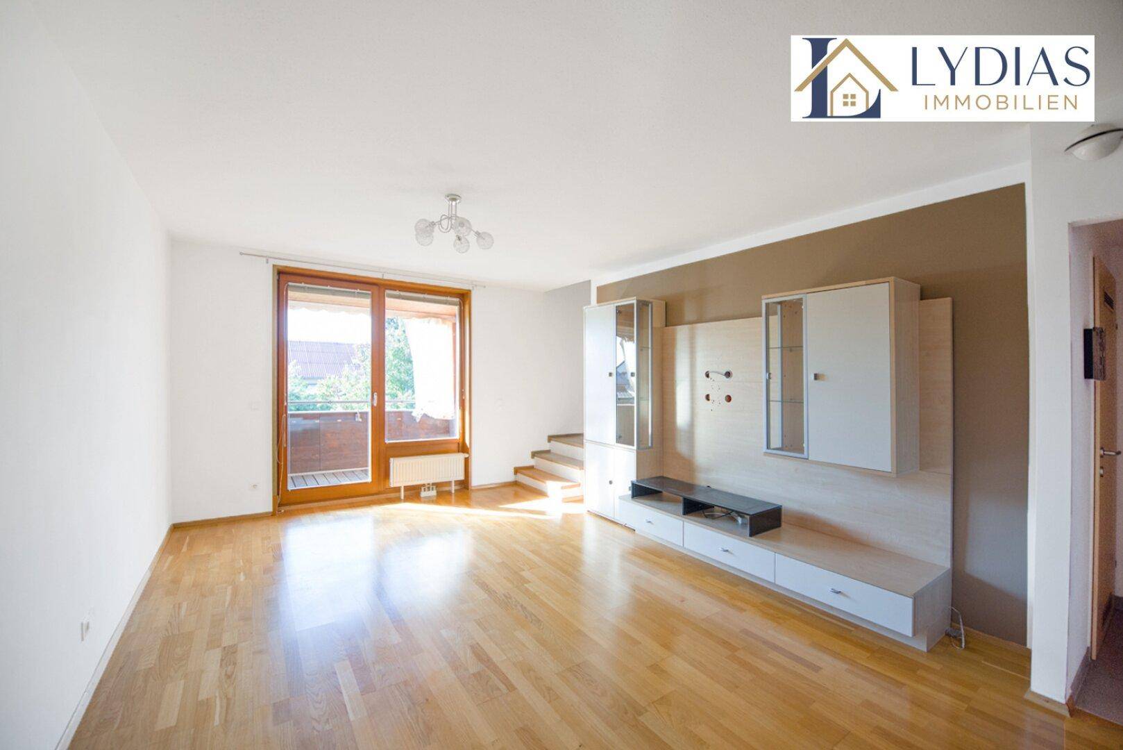 Heller Wohnbereich mit Holzboden und Zugang zum Balkon, ausgestattet mit modernen Möbeln.
