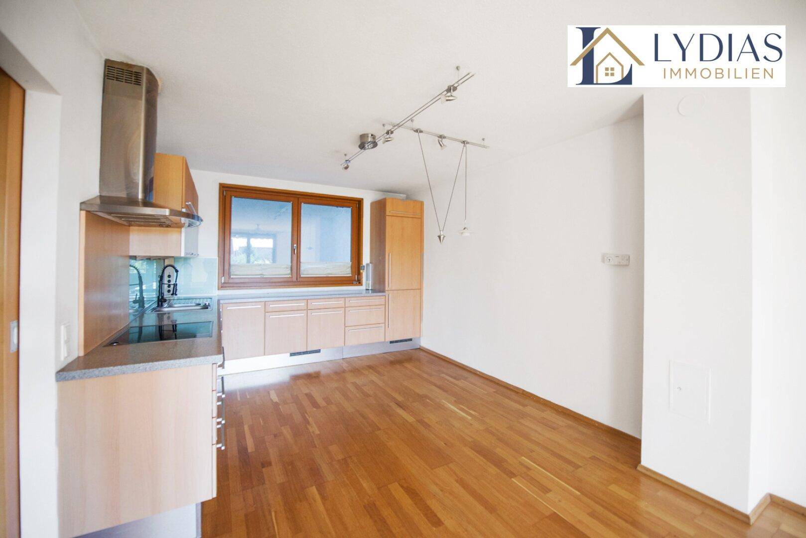 Moderne Einbauküche mit Holzfronten und Edelstahlgeräten, offen zum Wohnbereich.