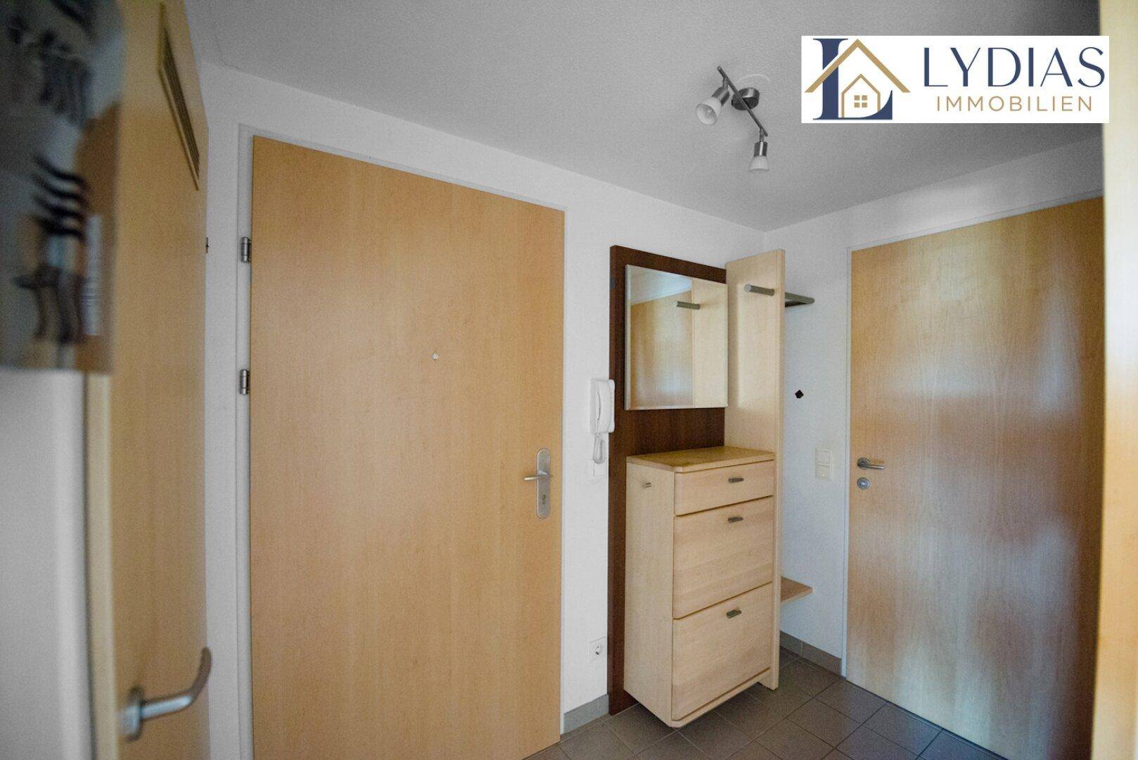 Eingangsbereich mit Garderobe und Spiegel, funktional und hell gestaltet.