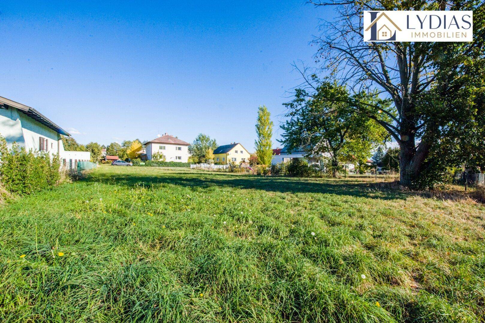 Große, gepflegte Rasenfläche eines Gartens mit Blick auf benachbarte Häuser und die weite Landschaft.