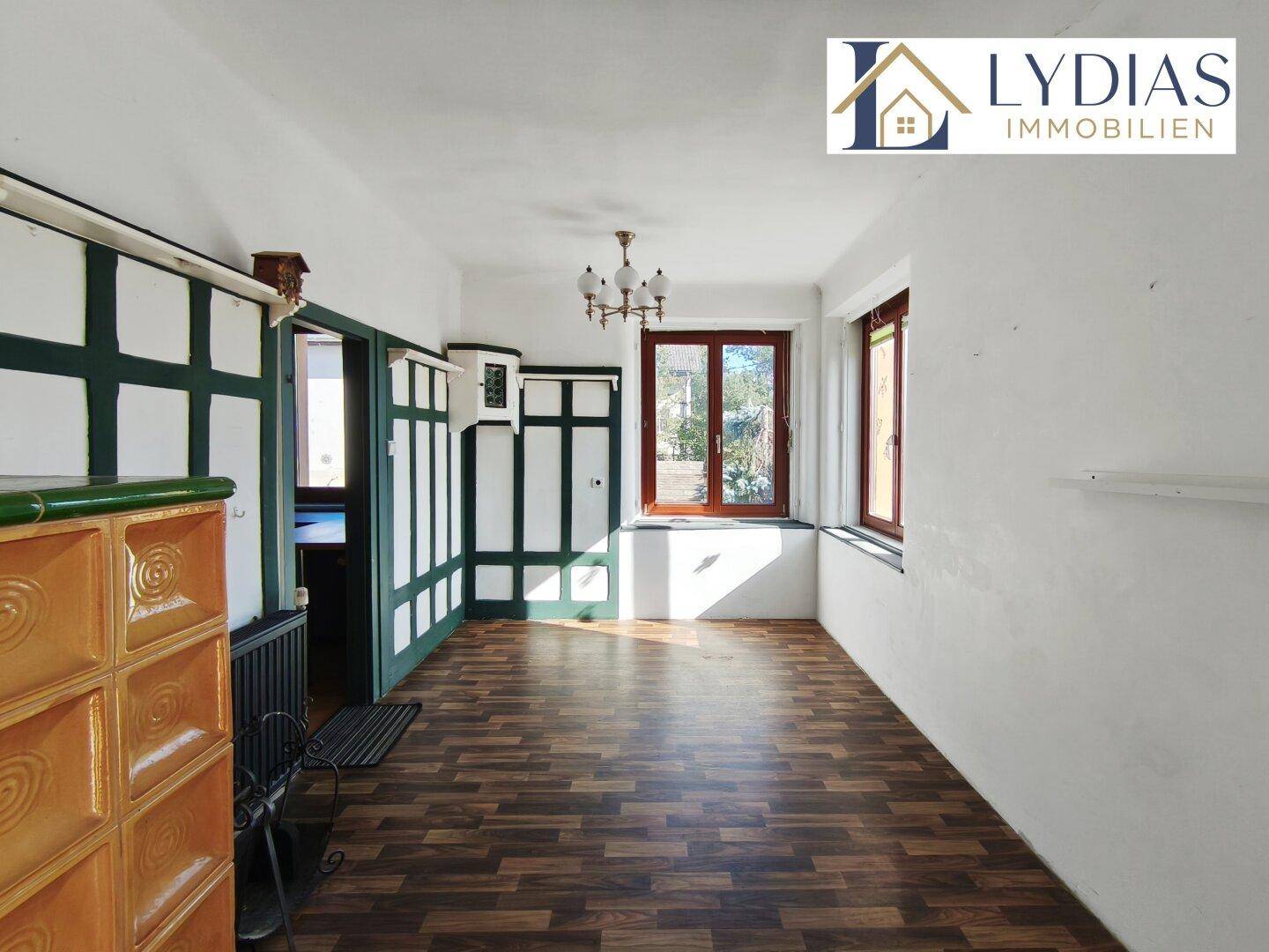 Traditionelles Zimmer mit Holzboden, Kachelofen und Holzvertäfelung.