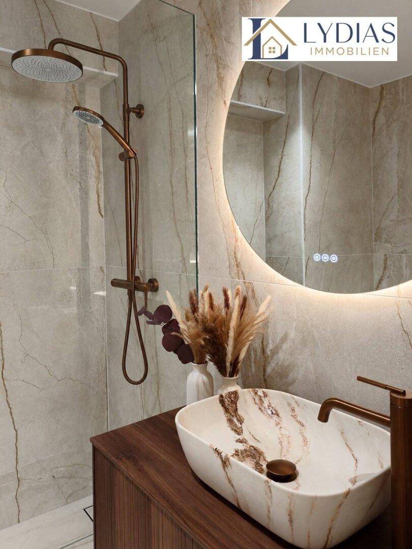 Elegantes Badezimmer mit stilvollem Aufsatzwaschbecken, beleuchtetem Spiegel und modernen Armaturen.