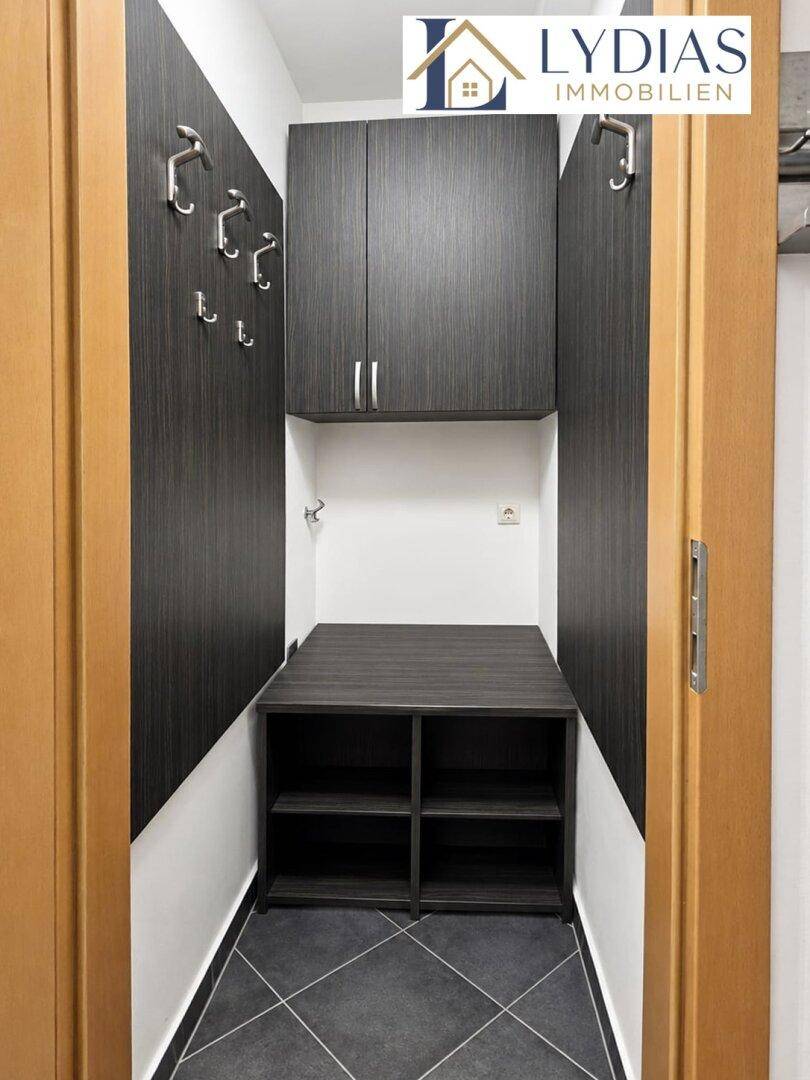 Praktischer Abstellraum oder Garderobenbereich mit dunklen Schränken und Haken.