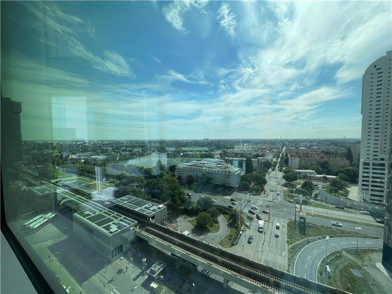 Weitläufiger Stadtblick von oben mit Fluss, Grünflächen und belebten Straßen.