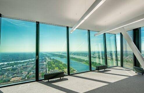 Sehr heller Büroraum mit raumhohen Glasfenstern und beeindruckendem Panoramablick auf die Umgebung.