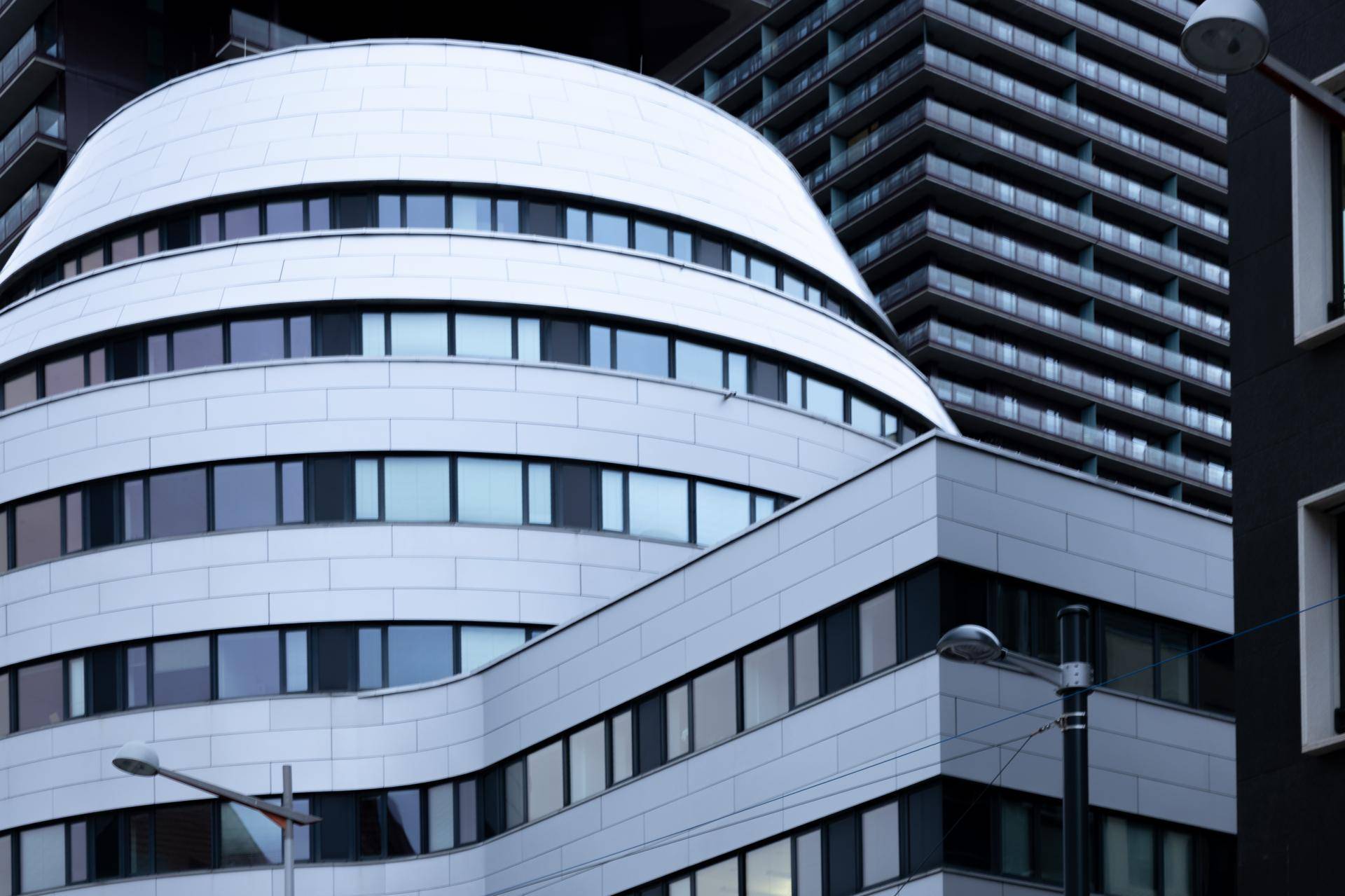 Detailansicht der geschwungenen, modernen Fassade eines Bürogebäudes mit vielen Fenstern.