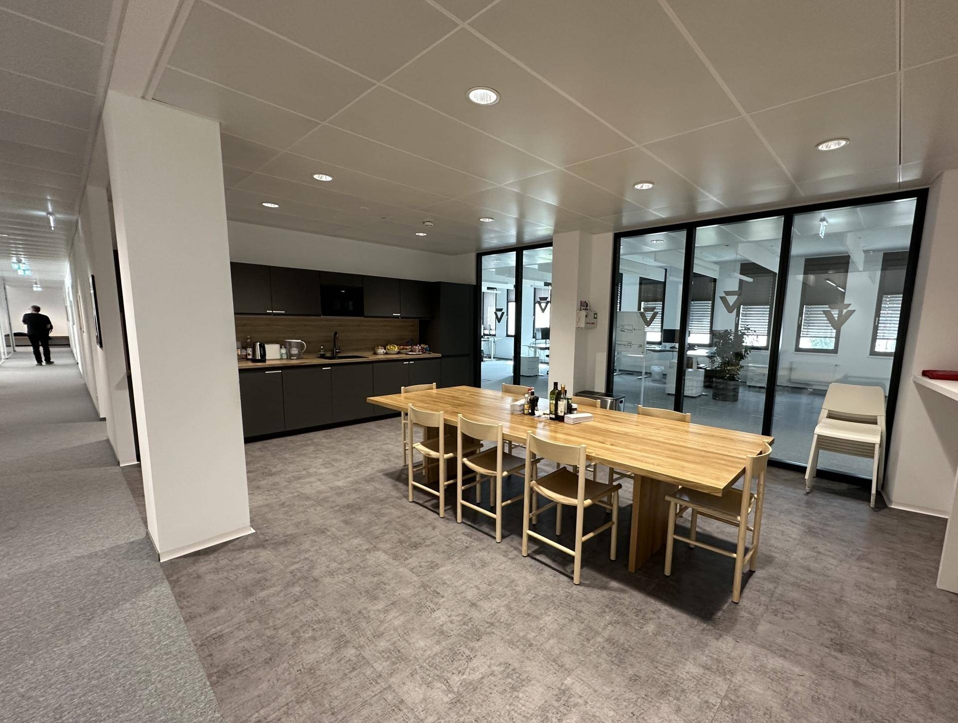 Offener Küchen- und Essbereich mit moderner Einbauküche und großem Holztisch für gemeinsame Mahlzeiten.