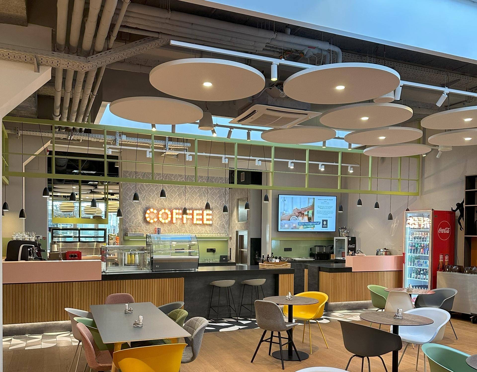 Lebhafter Café-Bereich mit modernen Möbeln, kreativer Deckenbeleuchtung und einer Kaffeebar.