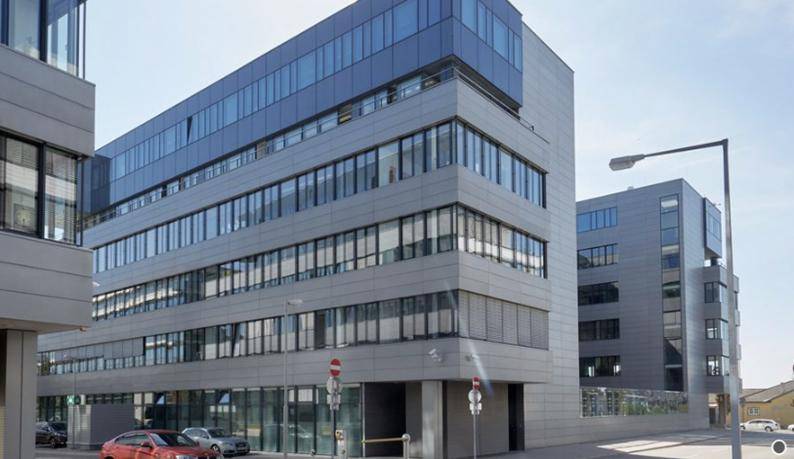 Modernes Bürogebäude mit mehreren Etagen, großen Fenstern und einer klaren, zeitgenössischen Architektur.