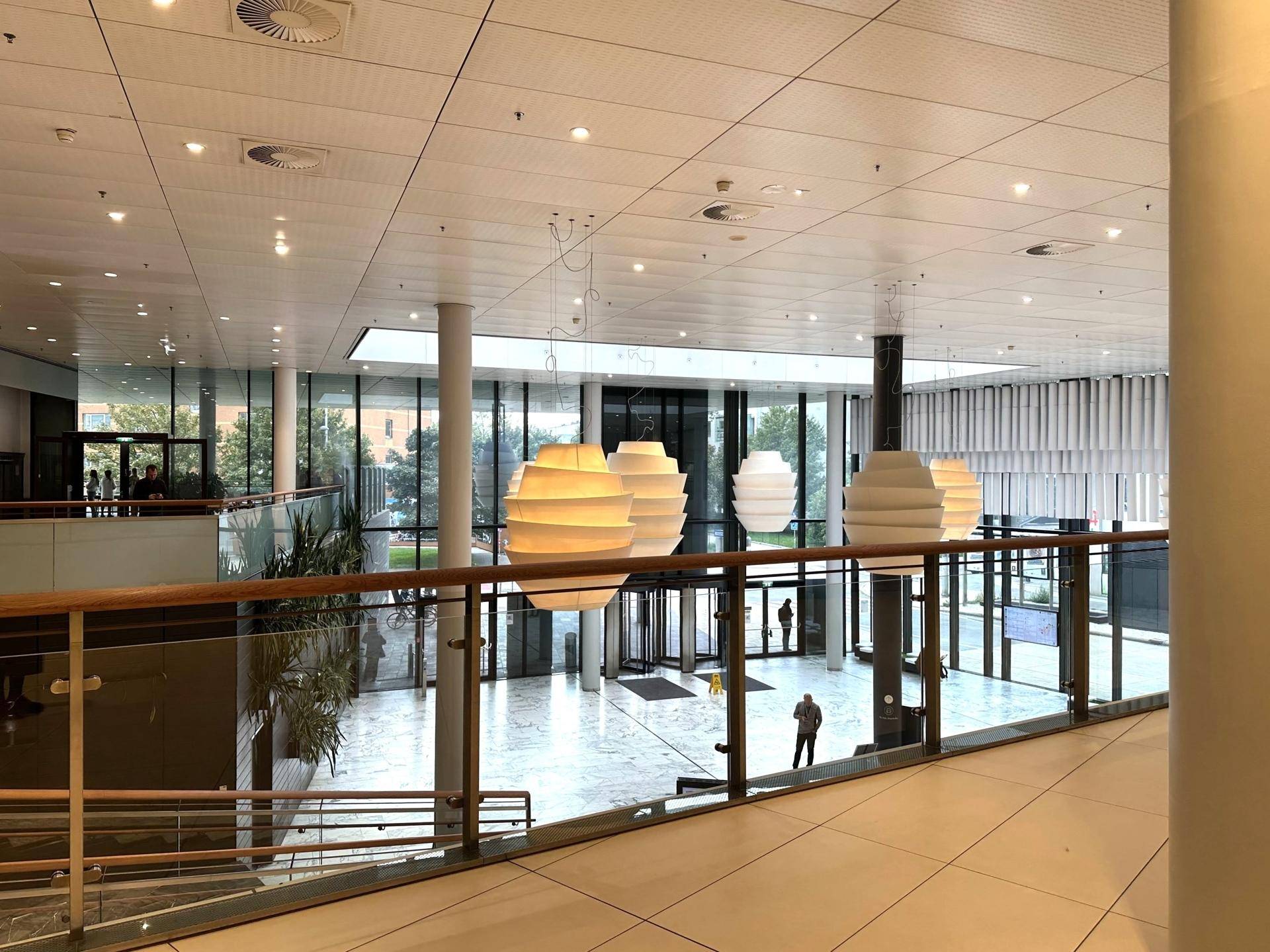 Großzügige, lichtdurchflutete Lobby mit hohen Decken und dekorativen Hängelampen.