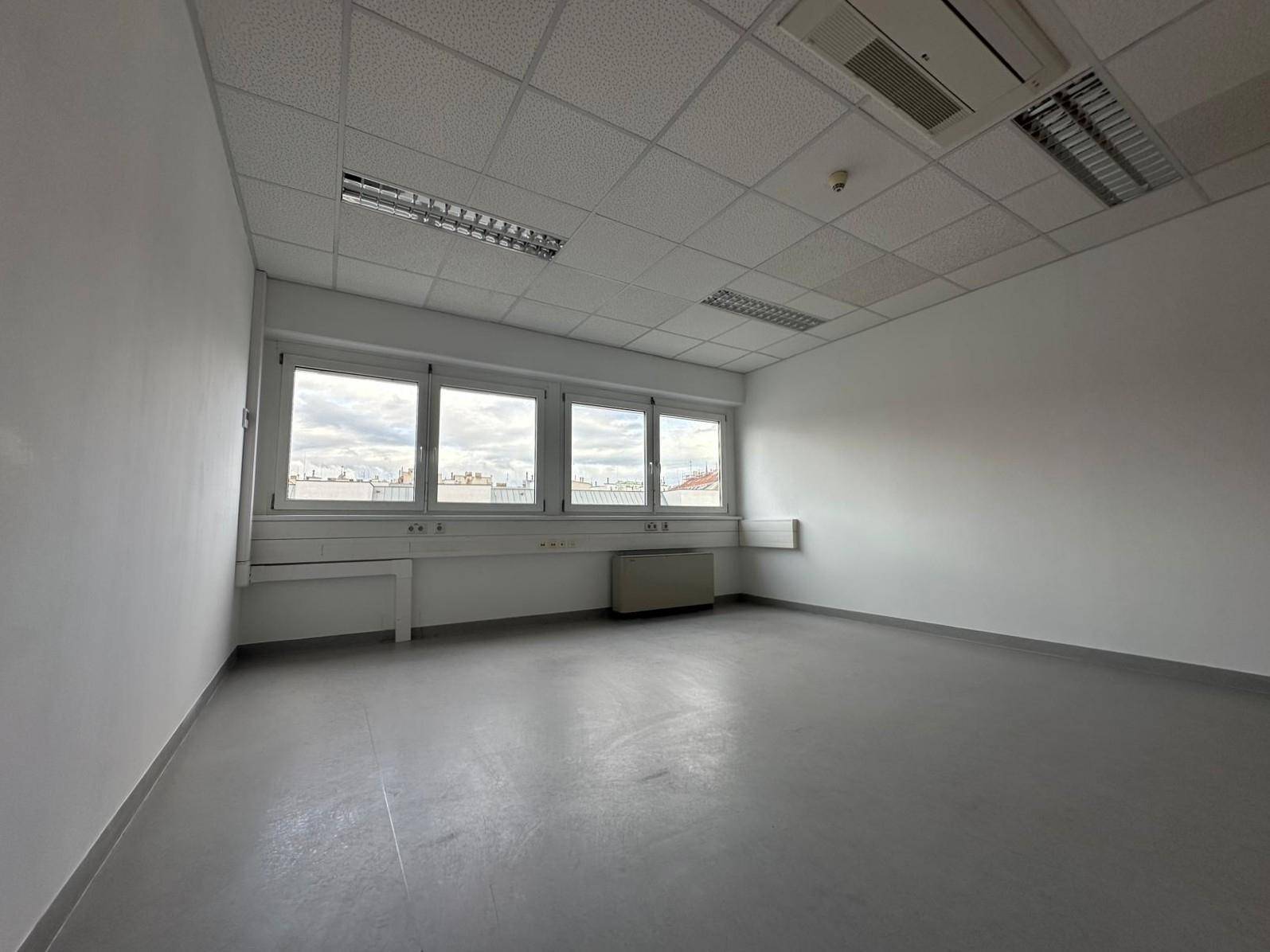 Geräumiges, leeres Büro mit Blick auf die Stadt durch die großen Fenster und Klimaanlage.