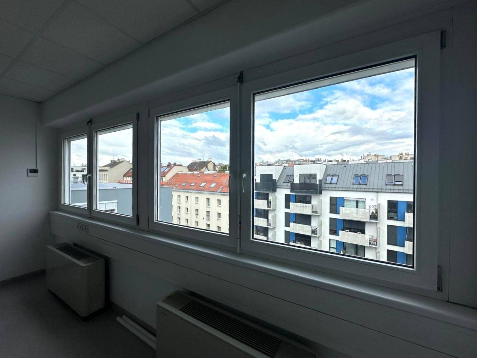 Nahaufnahme der Fensterfront eines Büros mit Blick auf die umliegenden Gebäude und den Himmel.